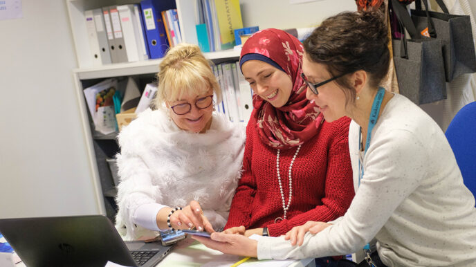 Kuvassa Riitta Palomäki, Dia Abu Abbas ja Elena Nuora katsovat älypuhelimen näyttöä.
