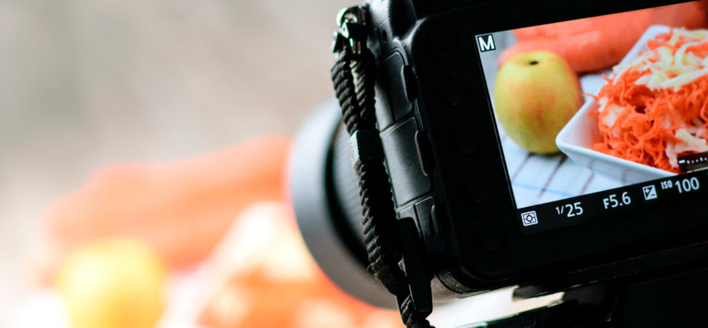 Etualalla digikamera joka kuvaa pöydälle asetettua ruokaa.