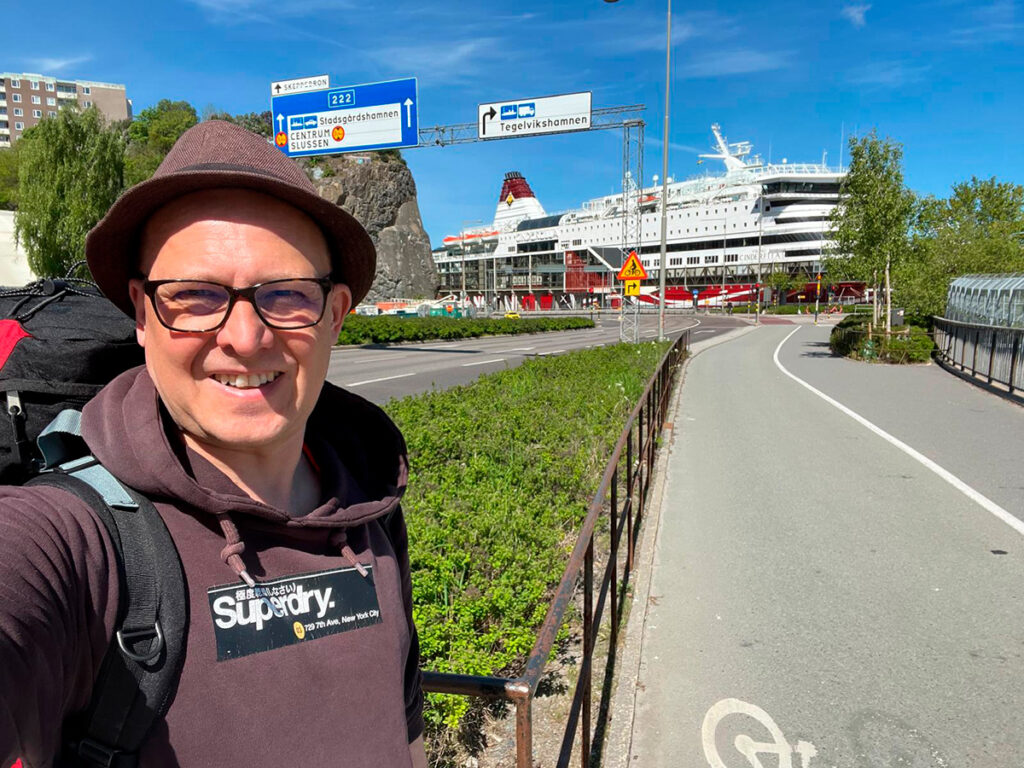 Etualalla hymyilevä henkilö, taustalla Ruotsin-laiva Tukholman satamassa