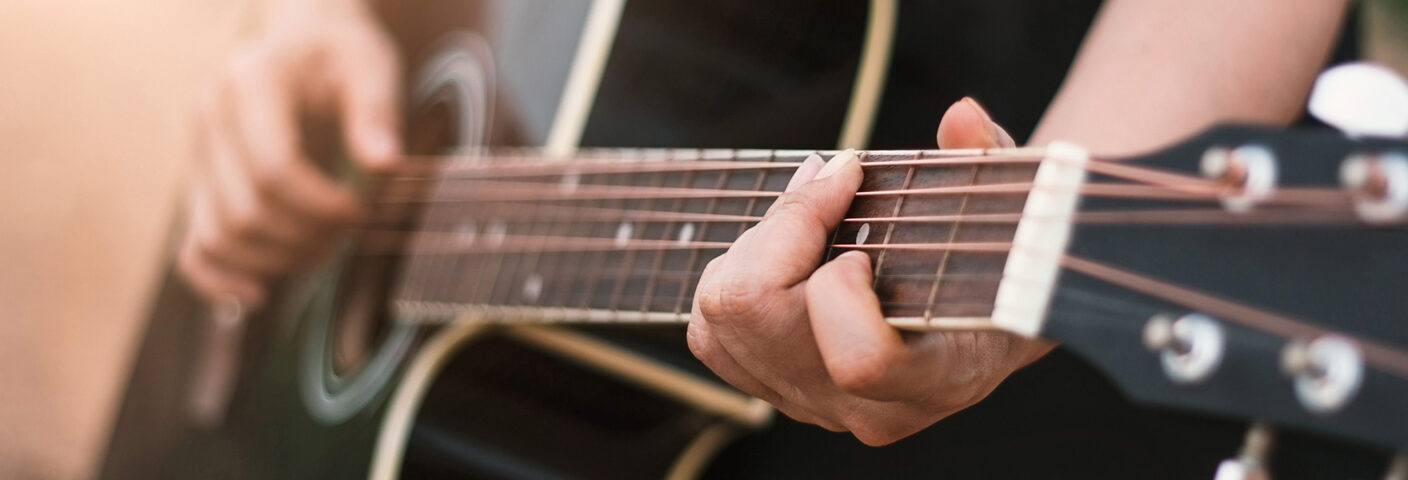 lähikuva kitaran otelaudasta ja soittajan käsistä